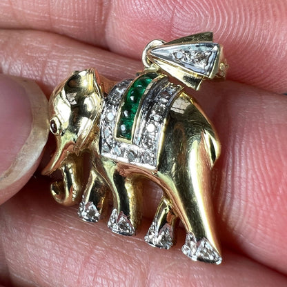 A yellow gold elephant pendant with rubies, emeralds and diamonds, held in a hand