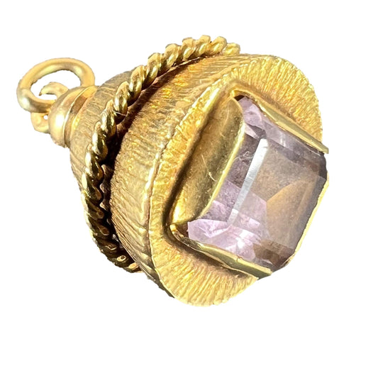 A yellow gold pendant with an amethyst set in the base, on a white background