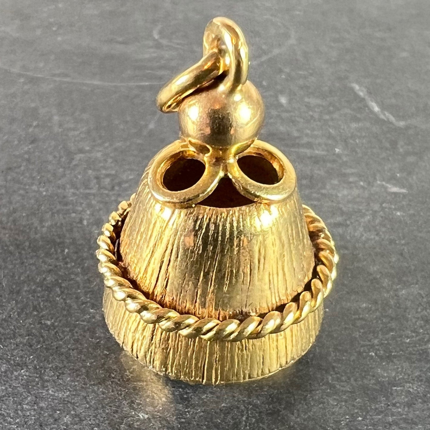 A yellow gold pendant, on a grey background