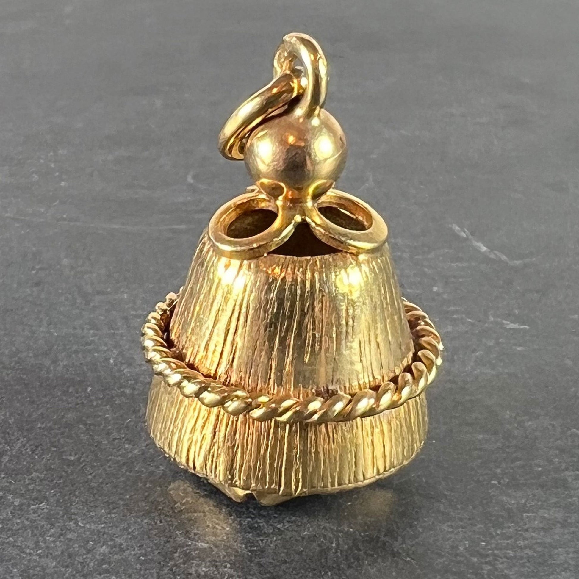 A yellow gold pendant, on a grey background