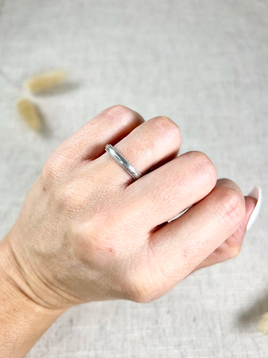 A platinum wedding band ring, modelled on a hand