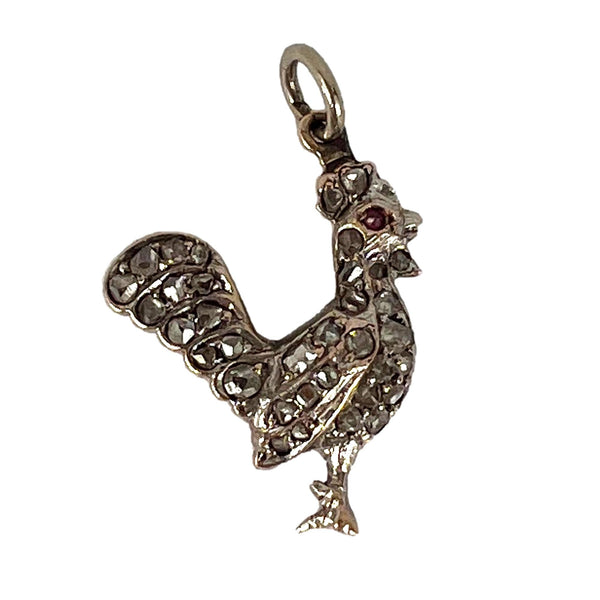 A rose cut diamond rooster pendant with a ruby eye, on a white background