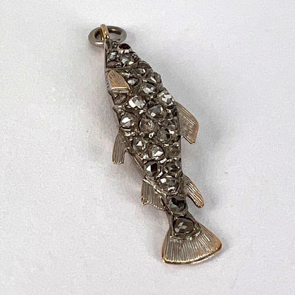 A fish shaped pendant with rose cut diamonds and ruby eye, on a white background