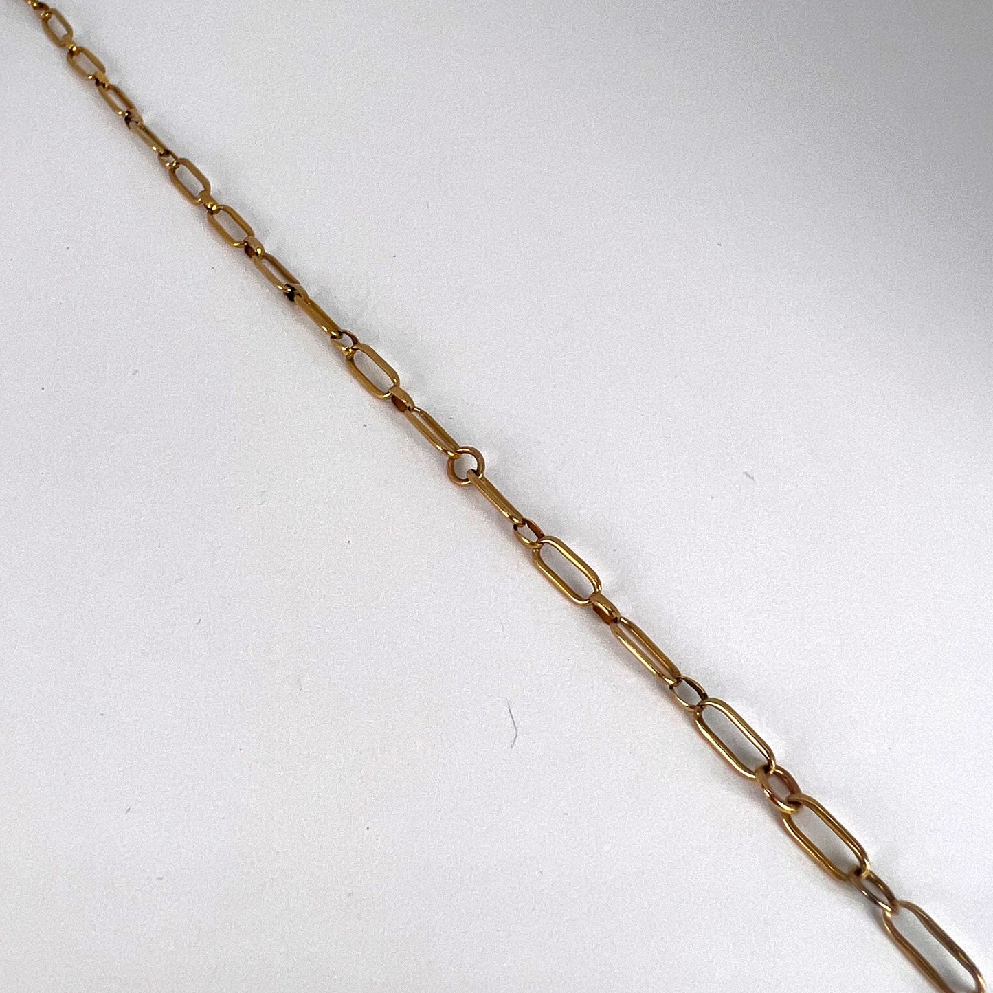 A yellow gold link bracelet with bolt ring clasp, on a white background