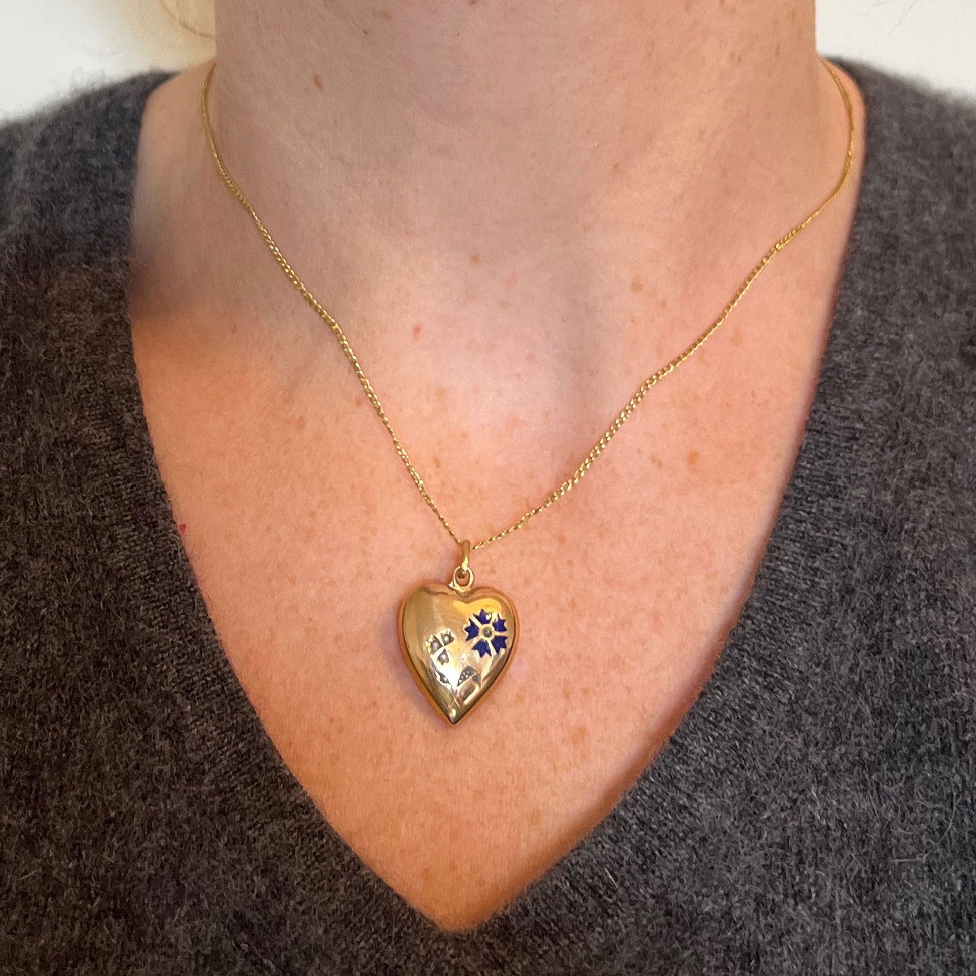 A yellow gold heart shaped pendant with enamel and seed pearls, modelled on a gold chain