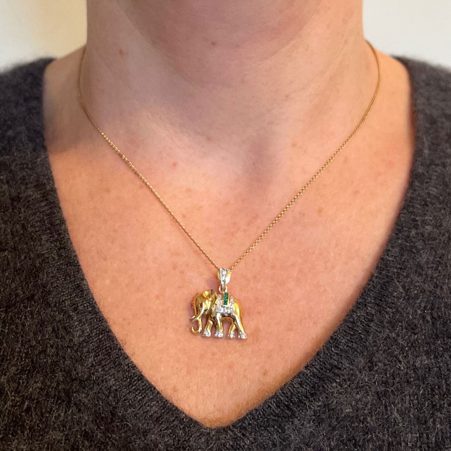 A yellow gold elephant pendant with rubies, emeralds and diamonds, modelled on a gold chain