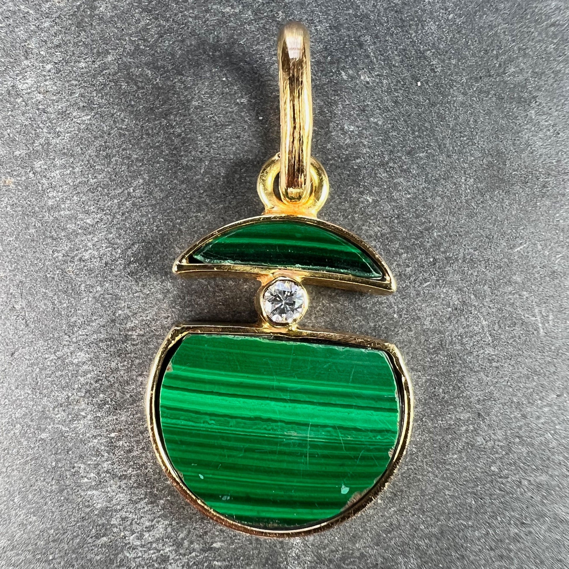 A malachite and diamond yellow gold split circle pendant, on a grey background