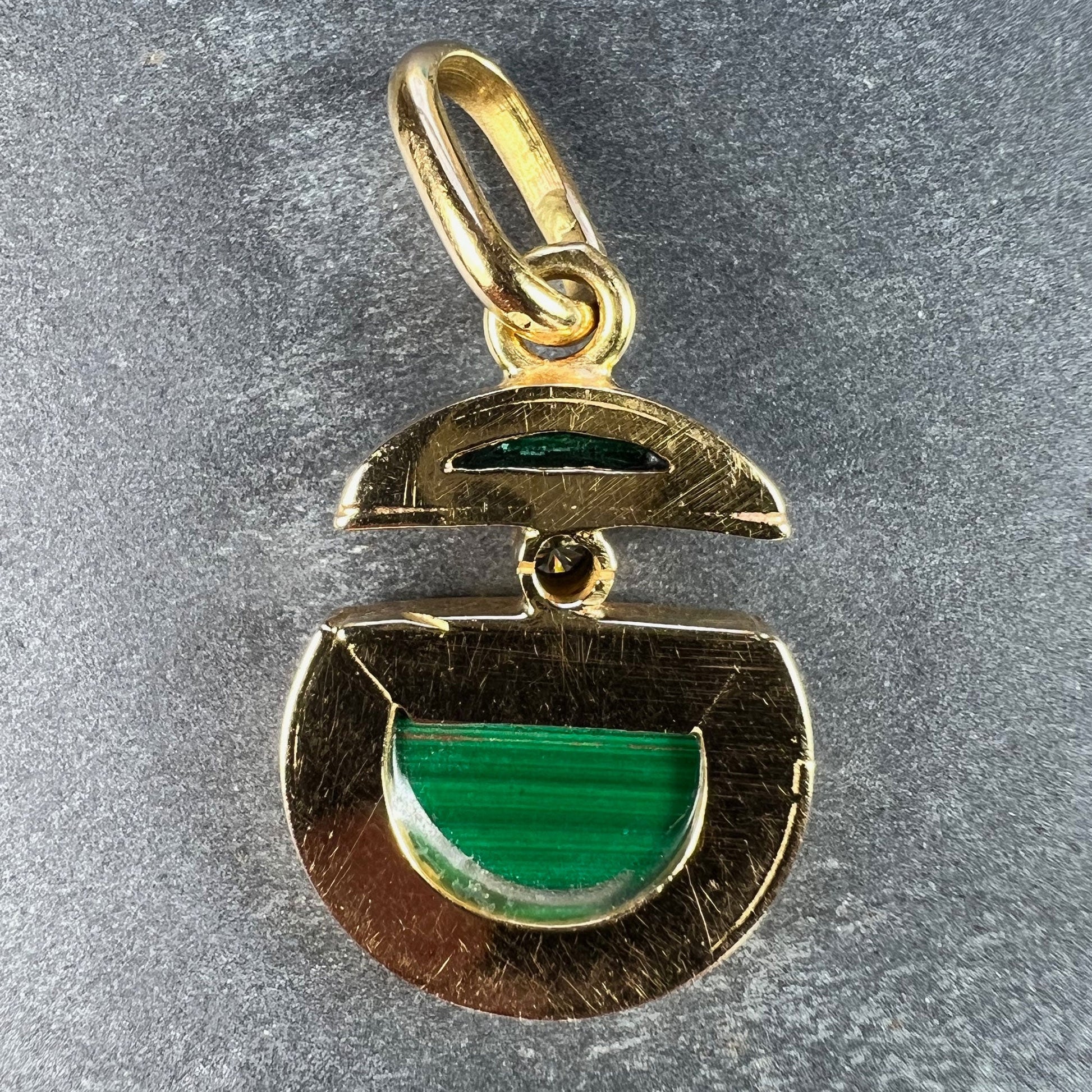 A malachite and diamond yellow gold split circle pendant, on a grey background