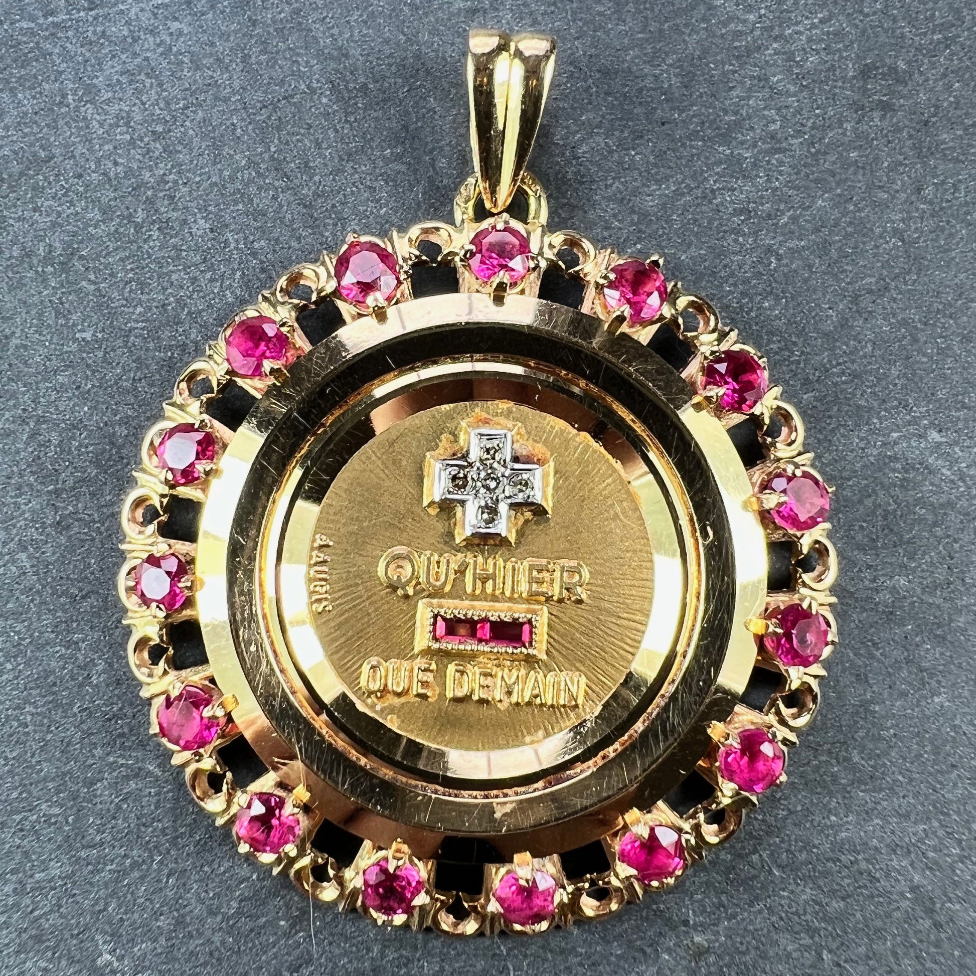 A French QU'HIER QUE DEMAIN pendant with diamonds and synthetic rubies, on a grey background