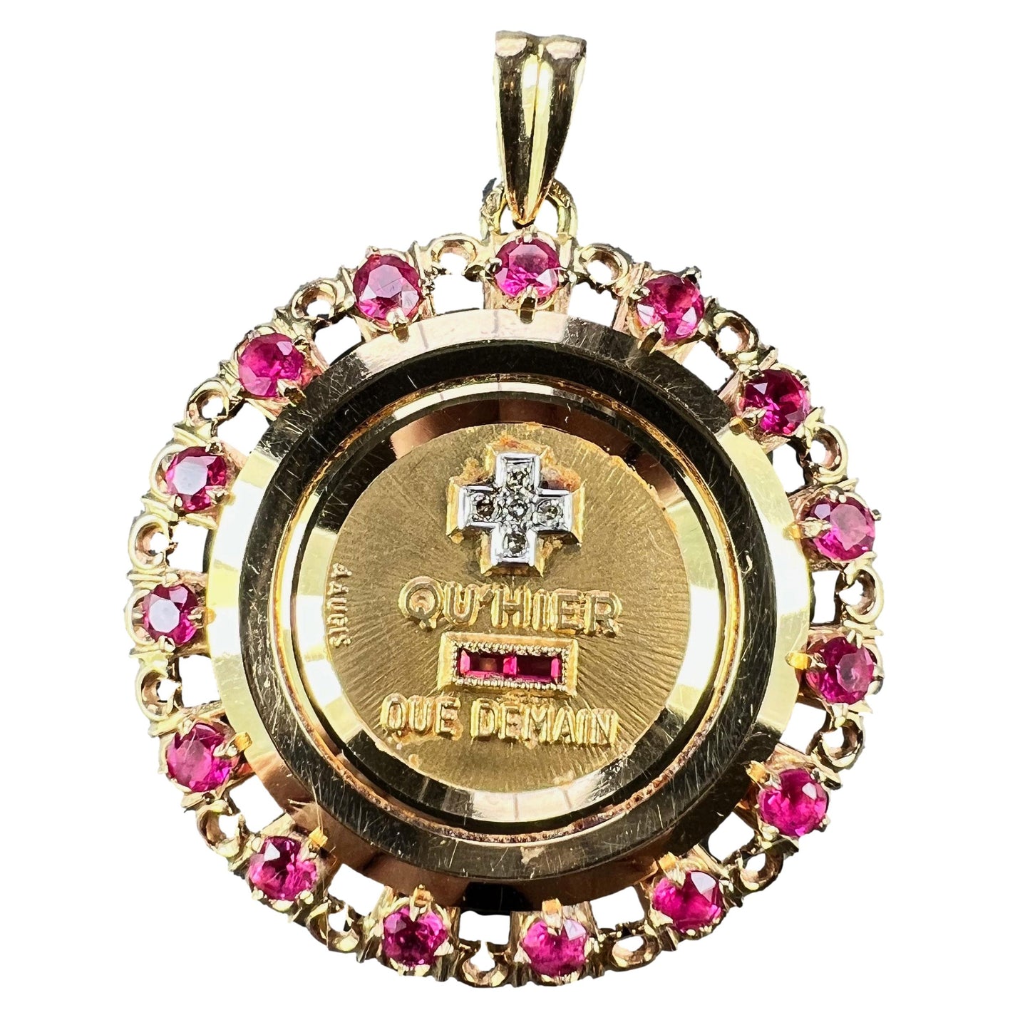 A French QU'HIER QUE DEMAIN pendant with diamonds and synthetic rubies, on a white background