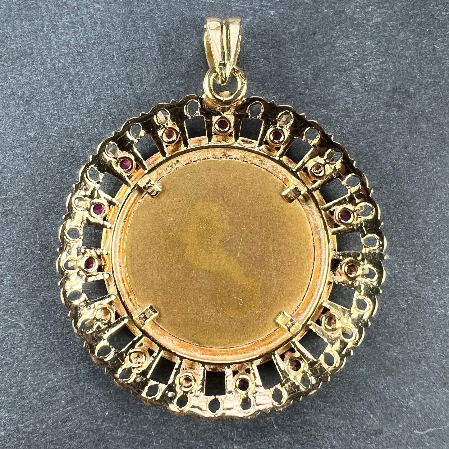 A round yellow gold pendant, on a grey background