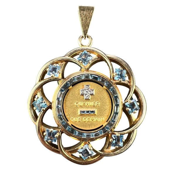 A yellow gold French QU'HIER QUE DEMAIN pendant with blue stones and diamonds, on a white background