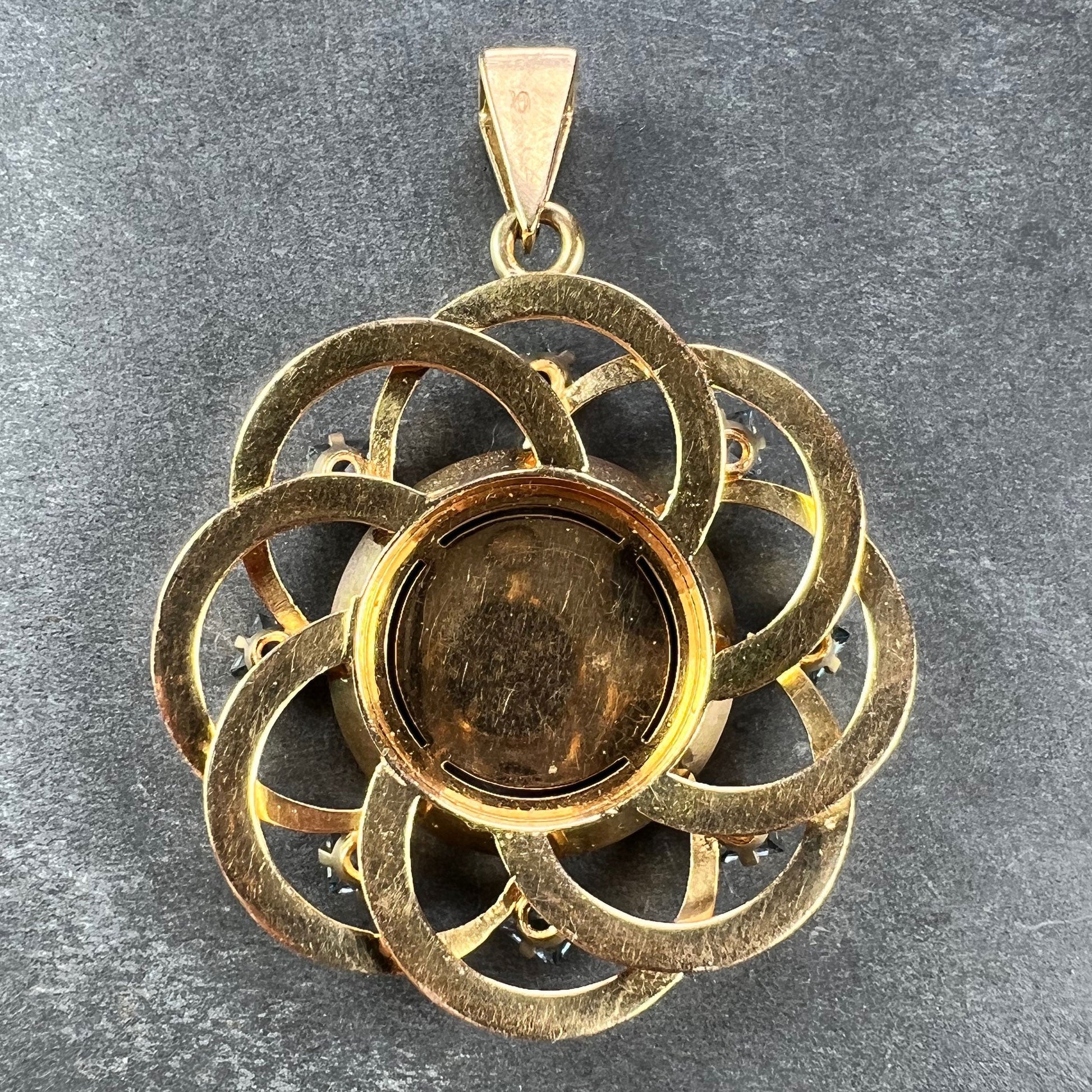 A yellow gold pendant, on a grey background