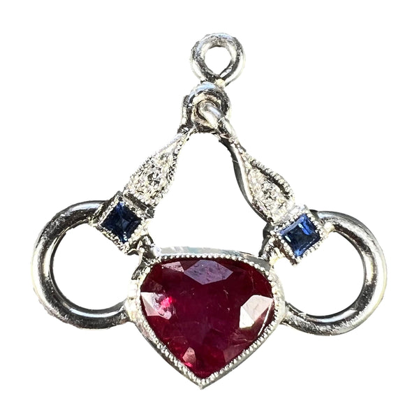 A heart shaped pendant with snaffle bits in white metal, with red, white and blue gemstones, on a white background