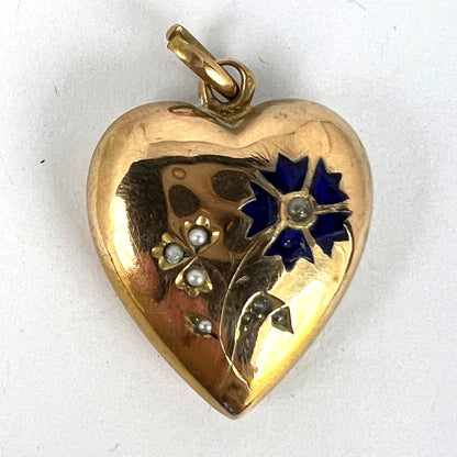 A yellow gold heart shaped pendant with enamel and seed pearls, on a white background