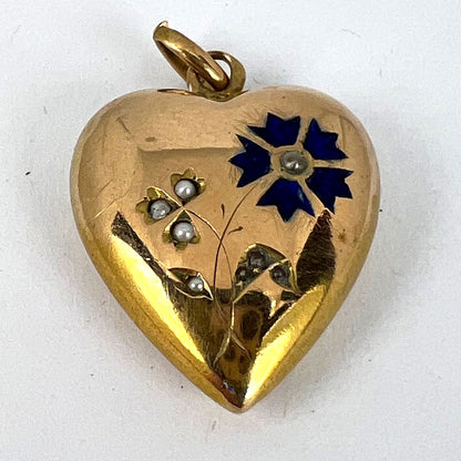 A yellow gold heart shaped pendant with enamel and seed pearls, on a white background