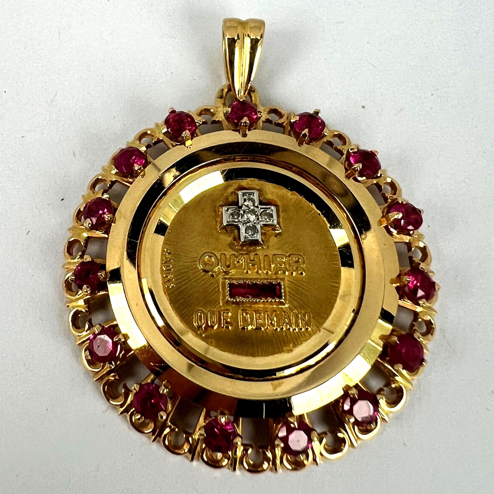 A French QU'HIER QUE DEMAIN pendant with diamonds and synthetic rubies, on a white background
