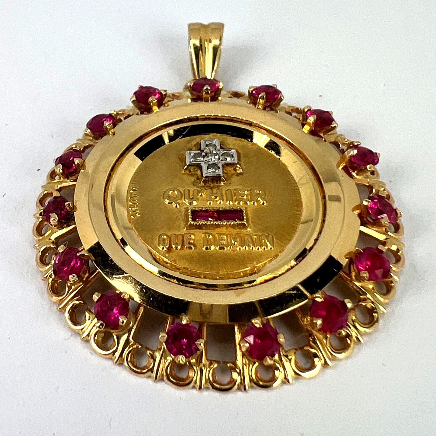 A French QU'HIER QUE DEMAIN pendant with diamonds and synthetic rubies, on a white background