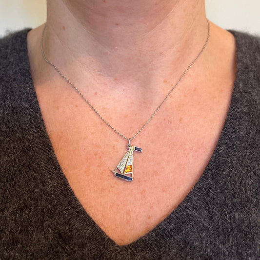 A white metal yacht sailboat pendant with diamonds, sapphires and citrines, modelled on a white metal chain