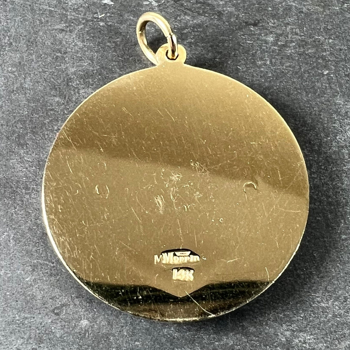 A round yellow gold pendant stamped Merrin and 14K