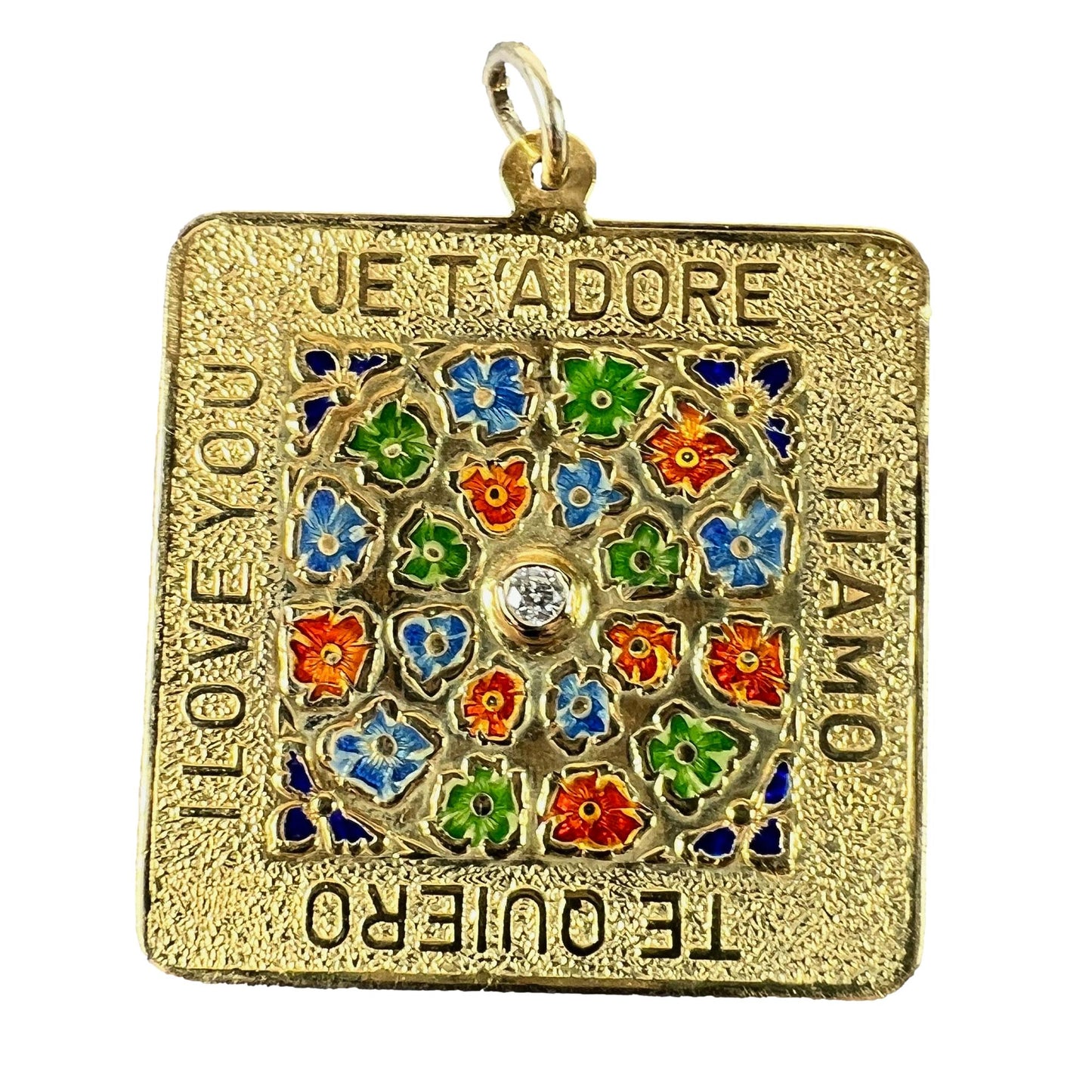 A square shaped yellow gold pendant with enamelled flowers and a central diamond, with text reading JE T'ADORE, TI AMO, TE QUIERO, I LOVE YOU