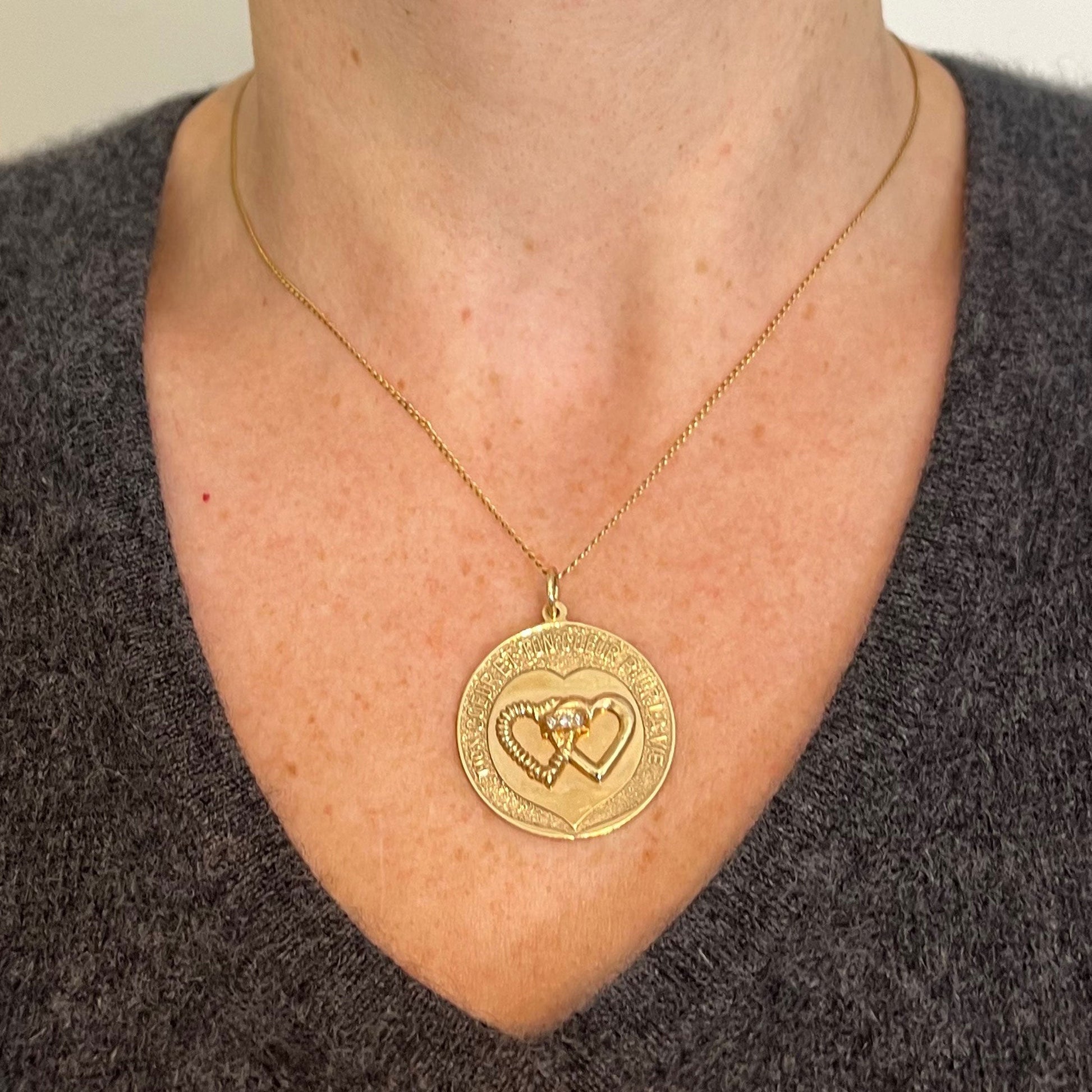 A round yellow gold love heart diamond pendant engraved MON COEUR ET TON COEUR POUR LA VIE, modelled on a gold chain