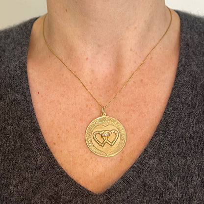 A round yellow gold love heart diamond pendant engraved MON COEUR ET TON COEUR POUR LA VIE, modelled on a gold chain