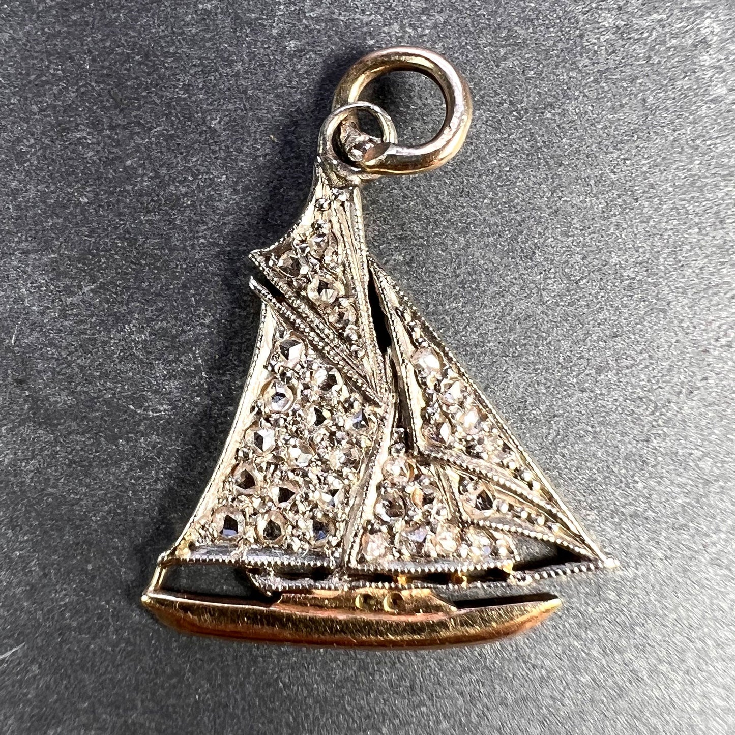 A diamond set yacht boat pendant, on a grey background