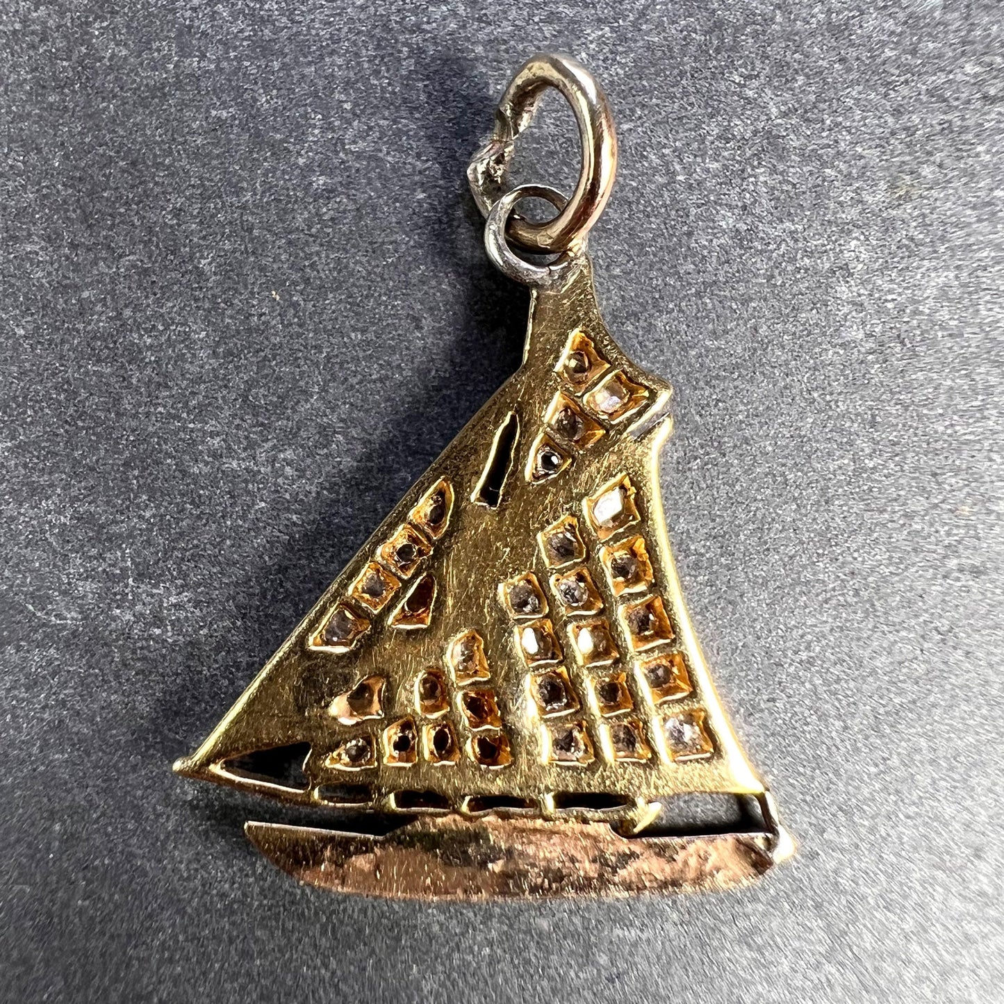 A diamond set yacht boat pendant, on a grey background