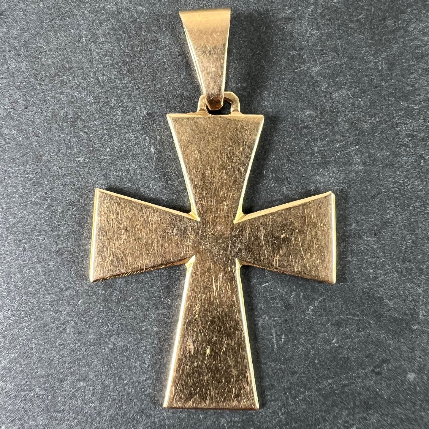 A plain gold cross pendant, on a grey background