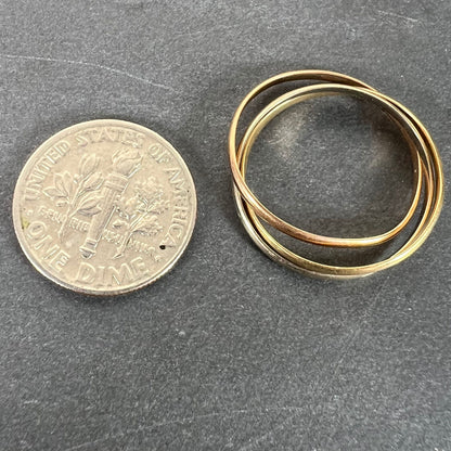 A tri-colour gold Russian wedding ring, next to a dime coin on a grey background