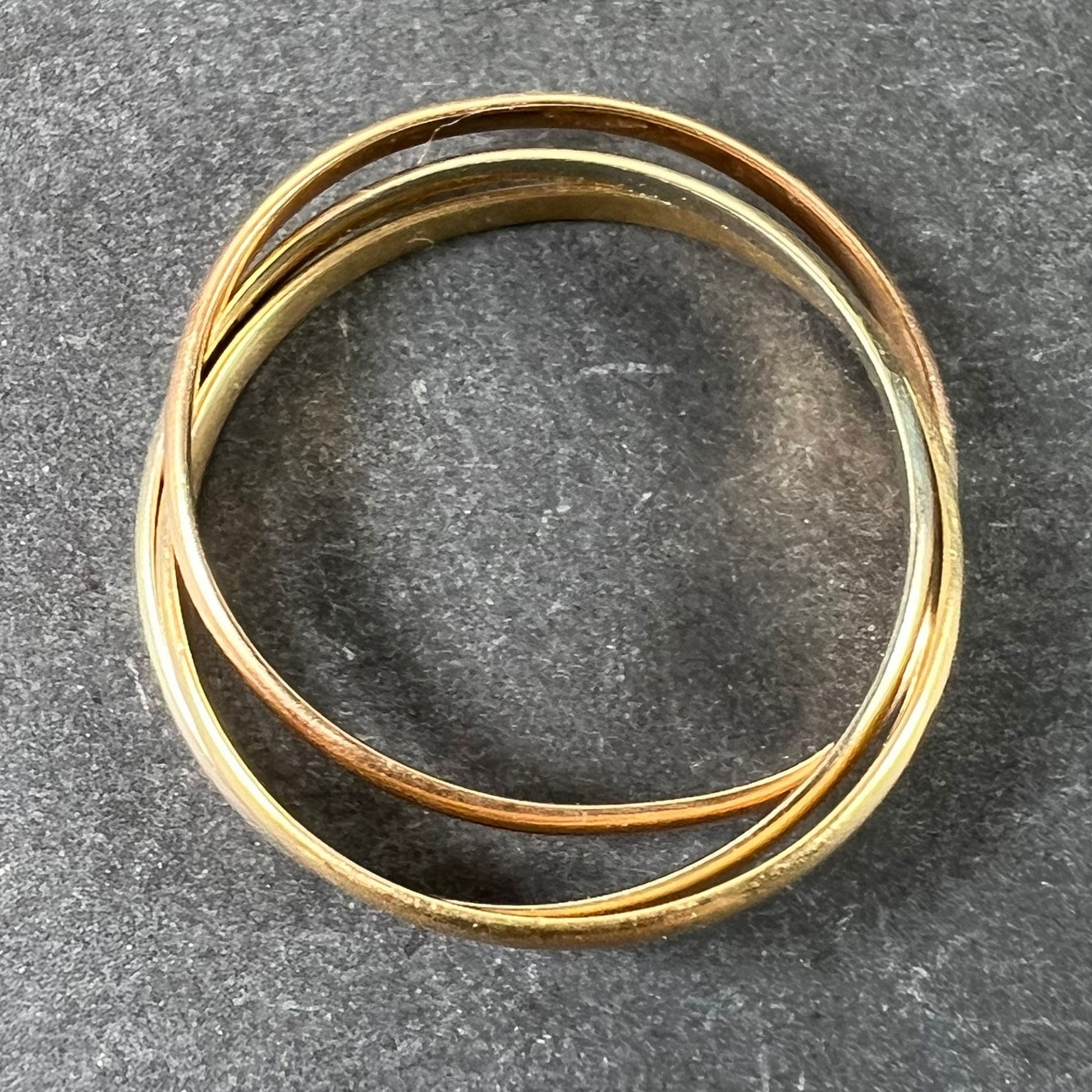 A tri-colour gold Russian wedding ring, on a grey background