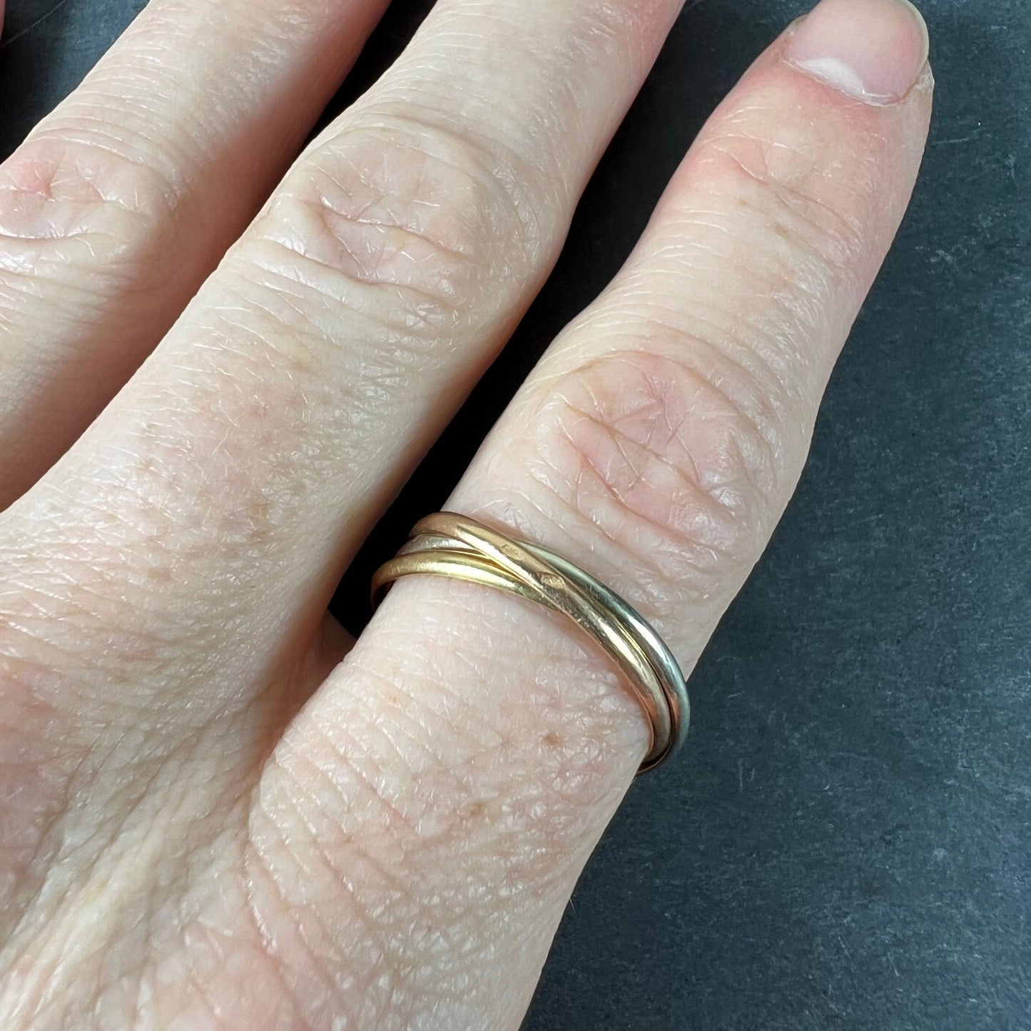 A tri-colour gold Russian wedding ring, modelled on a finger