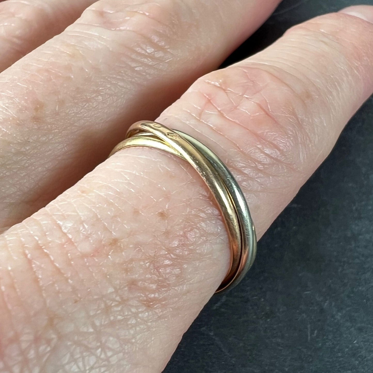A tri-colour gold Russian wedding ring, modelled on a finger