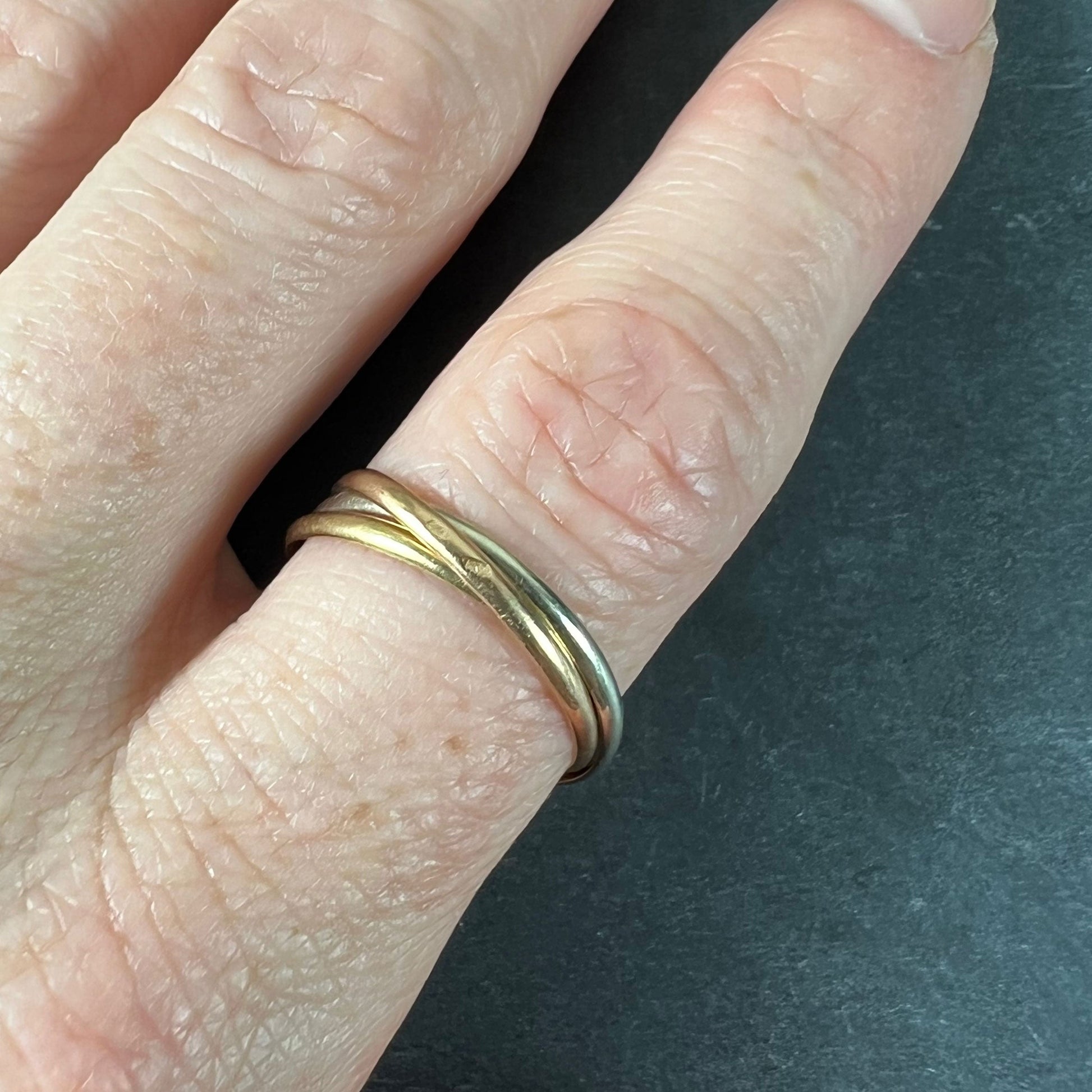 A tri-colour gold Russian wedding ring, modelled on a finger