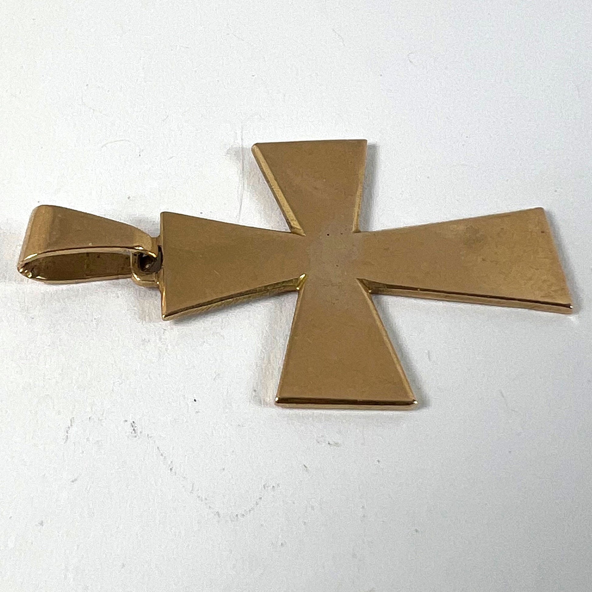 A plain gold cross pendant, on a white background