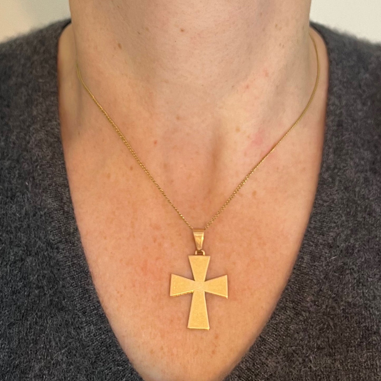 A plain gold cross pendant, modelled on a gold chain