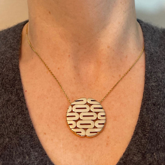 A gold oval motif circular pendant, modelled on a gold chain