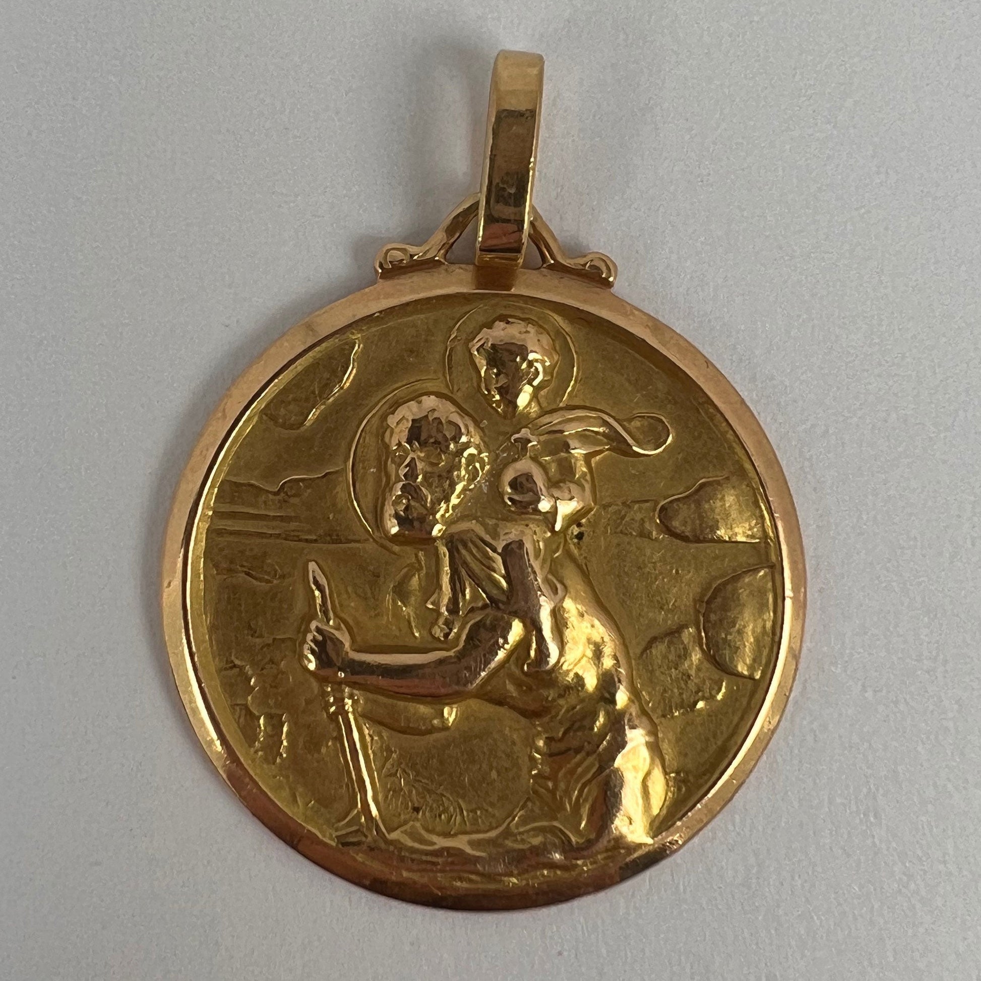A round yellow gold Saint Christopher pendant, on a white background