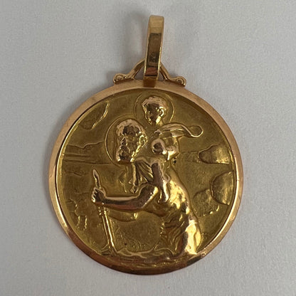 A round yellow gold Saint Christopher pendant, on a white background