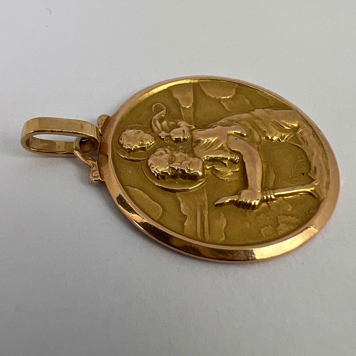 A round yellow gold Saint Christopher pendant, on a white background