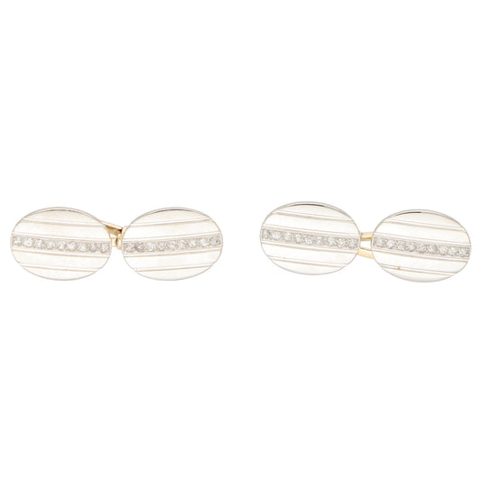 A pair of oval cufflinks in yellow and white metal set with diamonds, on a white background