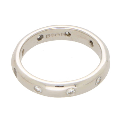 A platinum band ring with round damonds, on a white background