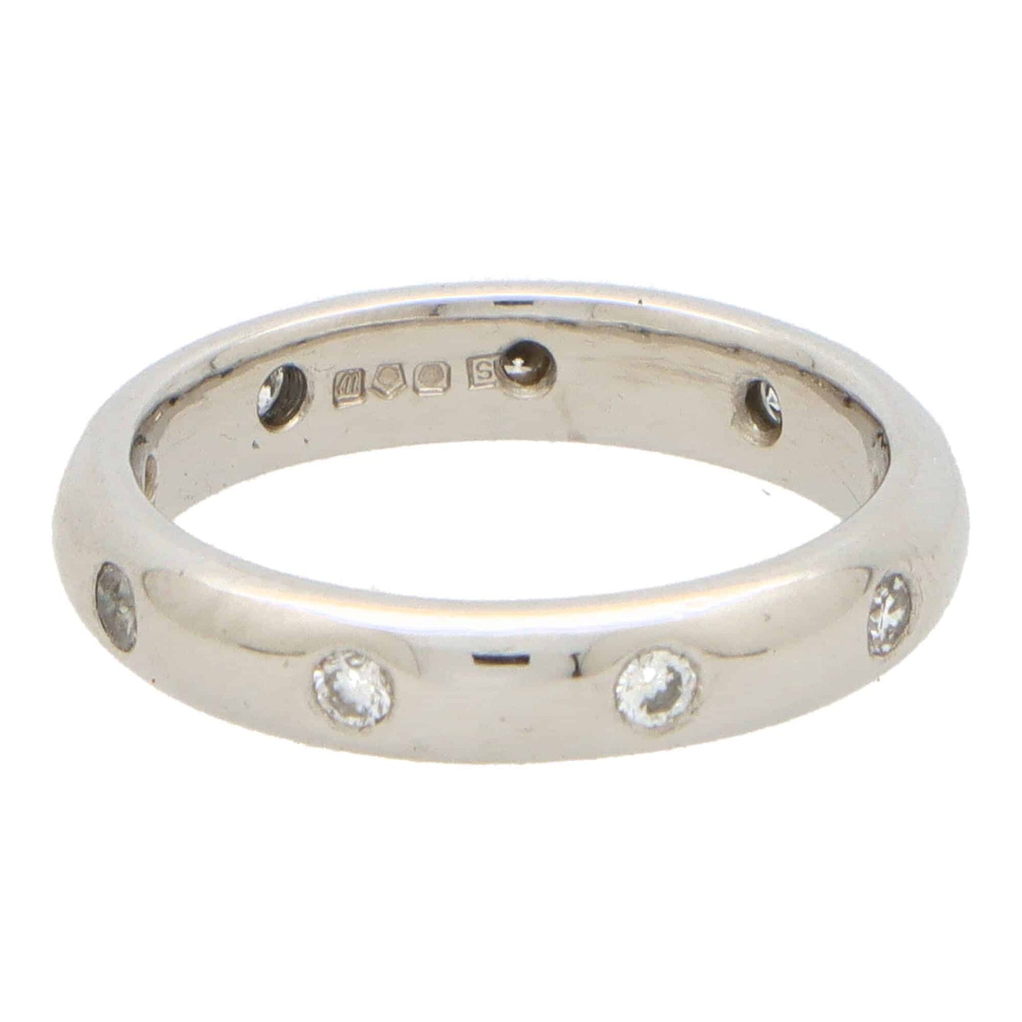 A platinum band ring with round damonds, on a white background