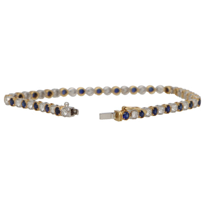 A sapphire and diamond line bracelet in yellow and white gold, on a white background