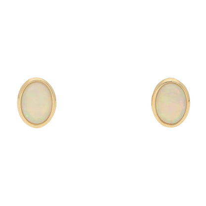 A pair of oval opal earrings in yellow gold, on a white background