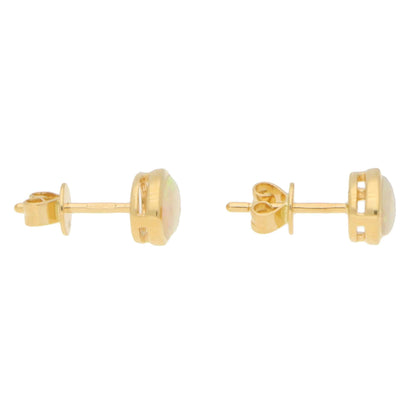 A pair of oval opal earrings in yellow gold, on a white background