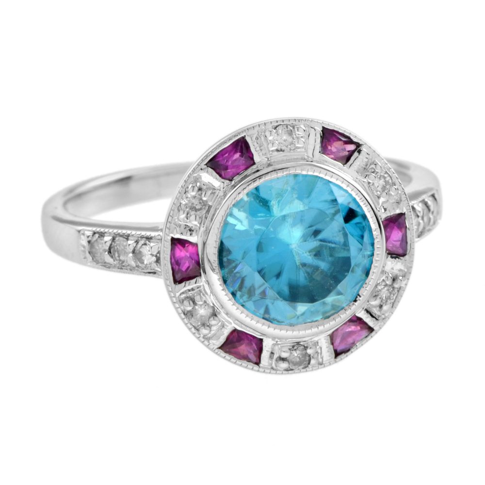 2.75ct Blue Zircon Ring with Ruby and Diamond Halo Cluster, central round-cut blue zircon is surrounded by rubies with a deep pink hue and diamonds with diamond-set shoulders in 14ct white gold