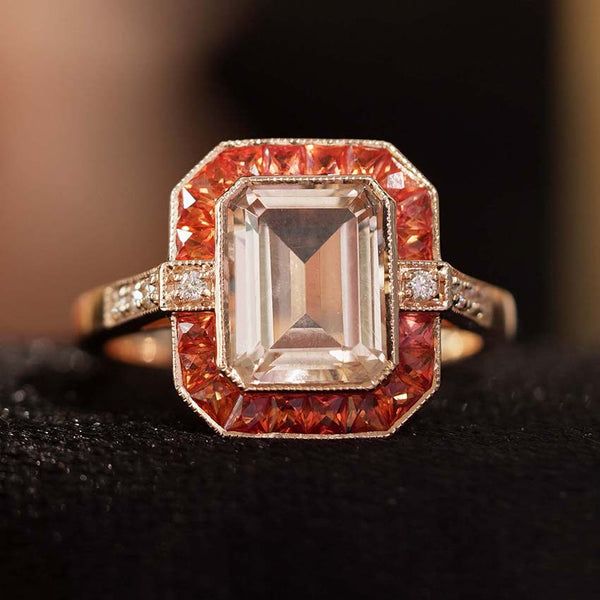 Emerald Cut Morganite and Orange Sapphire Cluster Ring with Diamond Shoulders, 2.25ct emerald-cut morganite framed by eye-catching French-cut orange sapphires in 14ct rose gold with diamond-set shoulders