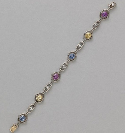 Art Deco Multi Colour Sapphire and Diamond Bracelet; oval links set with a natural facetted oval sapphire; two yellow, two pink and two blue, accented with rose cut diamonds and white sapphires, in silver and gold, Circa 1920